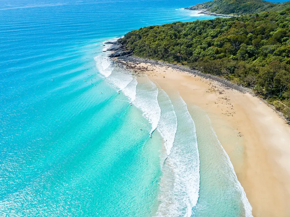 Tea Tree Bay from above, waves rolling in under the headland